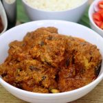 close-up of chicken rendang in a white bowl.