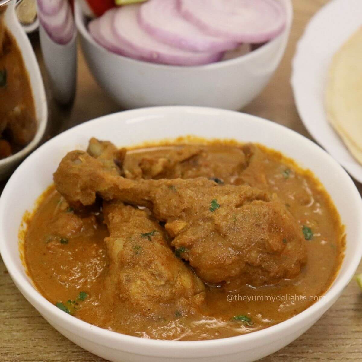 close-up of chicken salna in a white bowl. Served with parotta and salad.