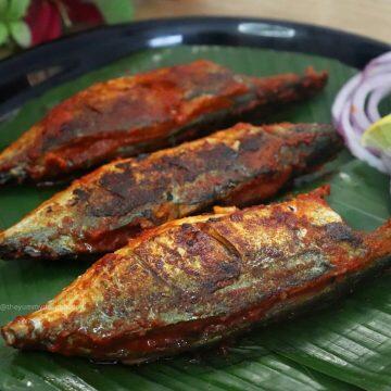 close-up of recheado mackerels served on a plate with lemon wedges and onion rings. Recheado masala fish recipe.