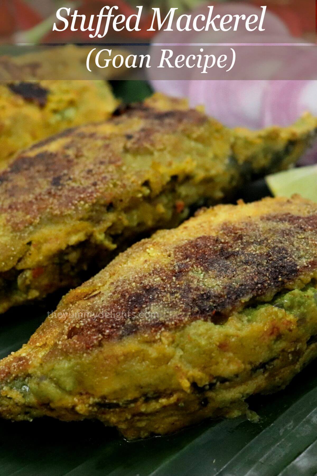 close up of stuffed mackerel with goan green masala. Served with onion rings and a lemon wedge on side.