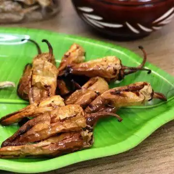 close up of curd chillies on a green color plate. These sun-dried curd chilies are fried in hot oil until crisp and golden.