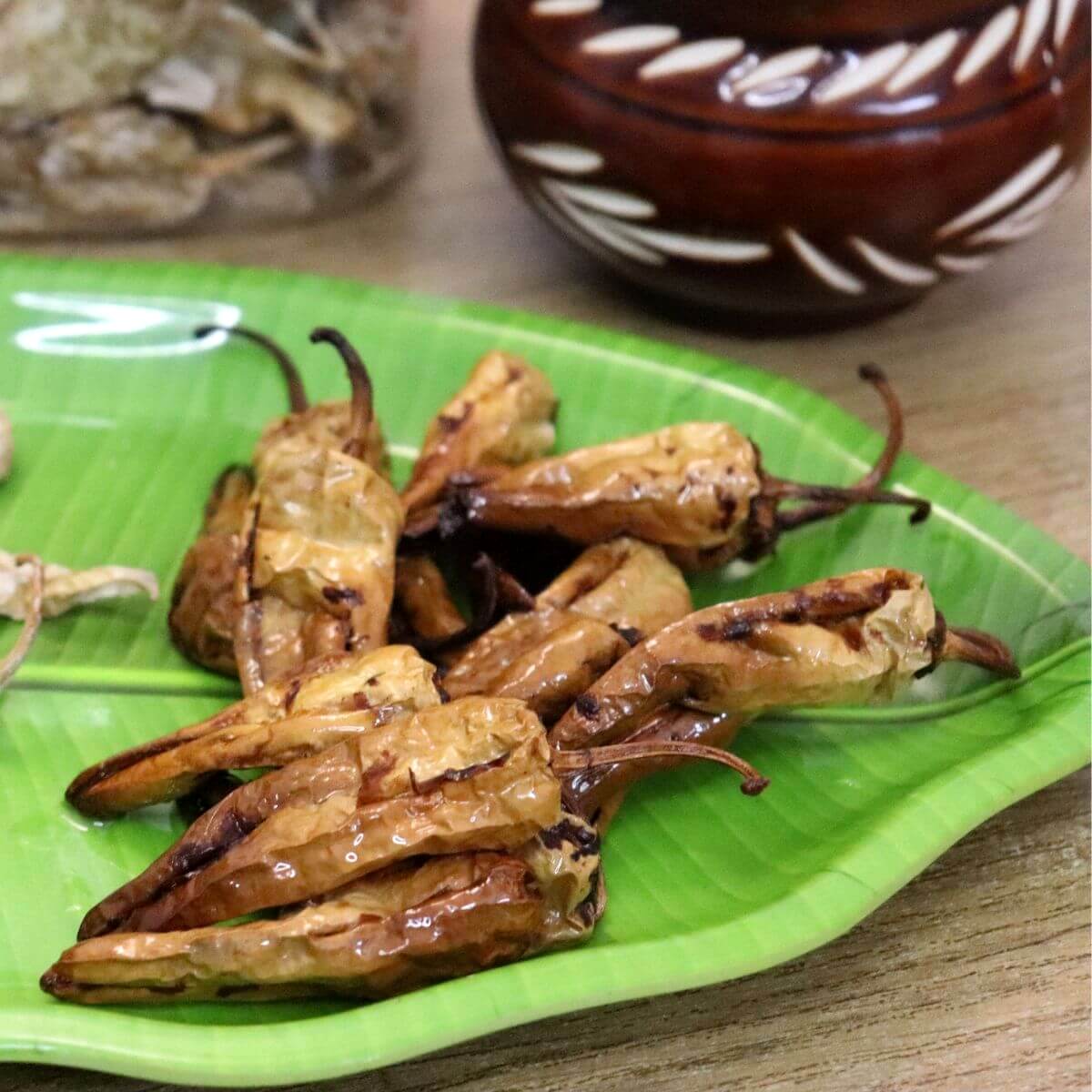 close up of curd chillies on a green color plate. These sun-dried curd chilies are fried in hot oil until crisp and golden.