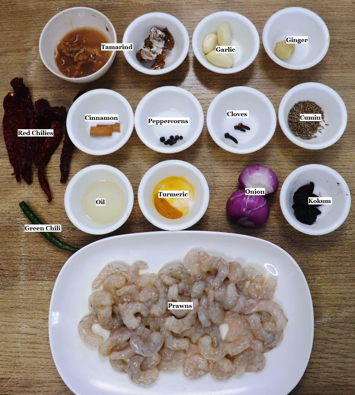 individually labeled ingredients to make goan prawn ambot tik recipe are laid out on a table.