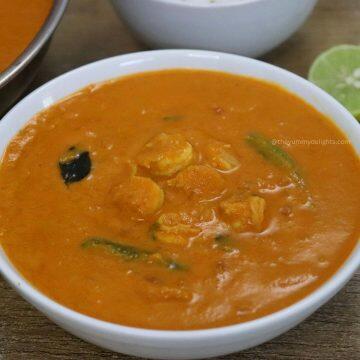 close-up of goan prawn curry recipe served in a white bowl iwh steamed rice and a lemon slice.