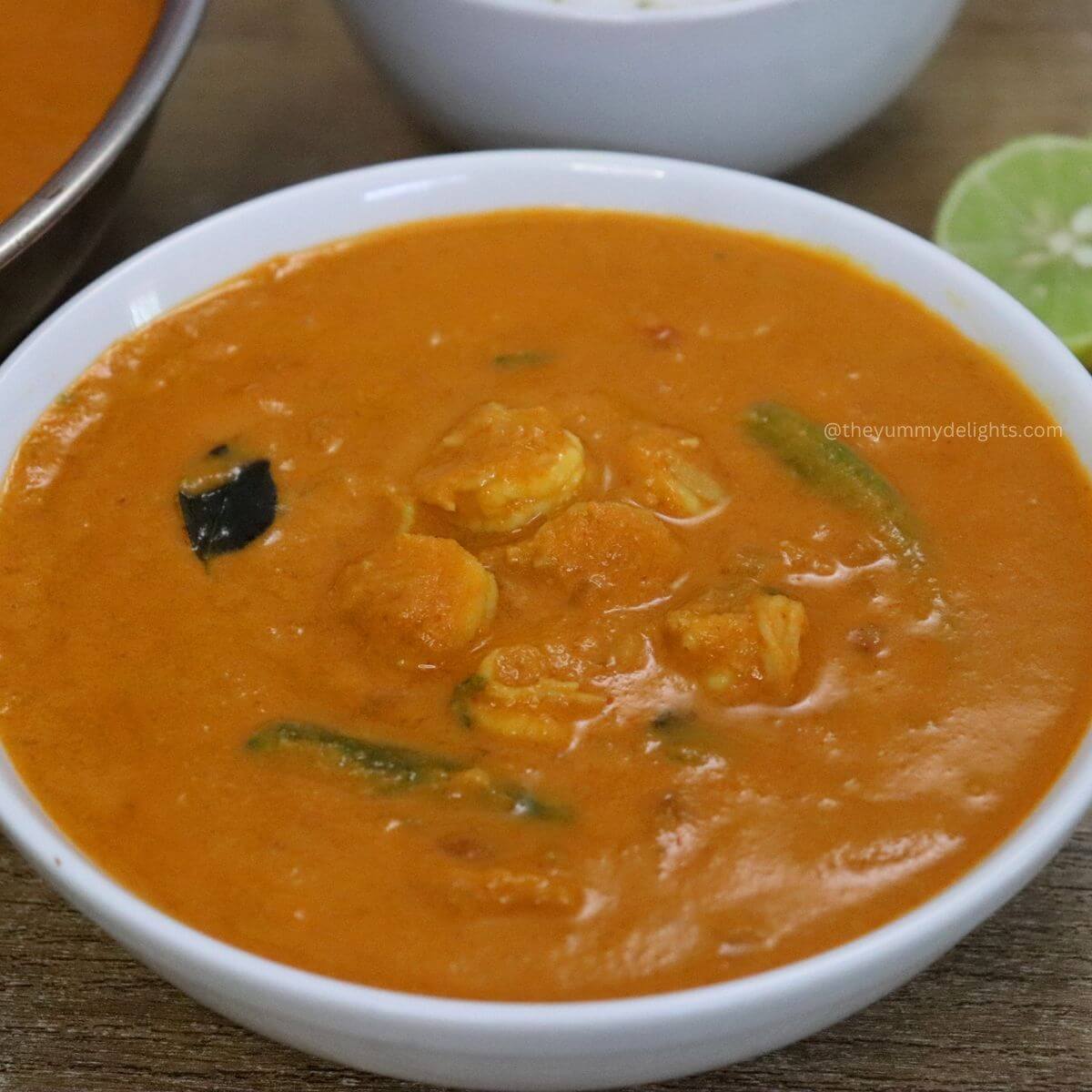 close-up of goan prawn curry recipe served in a white bowl iwh steamed rice and a lemon slice.