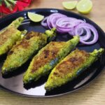 close-up of 4 green masala fish fry served on a plate with onion rings and lemon wedges on side.