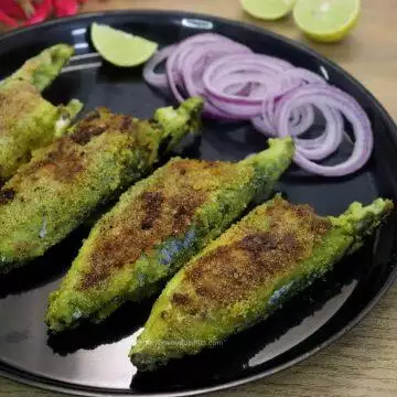 close-up of 4 green masala fish fry served on a plate with onion rings and lemon wedges on side.