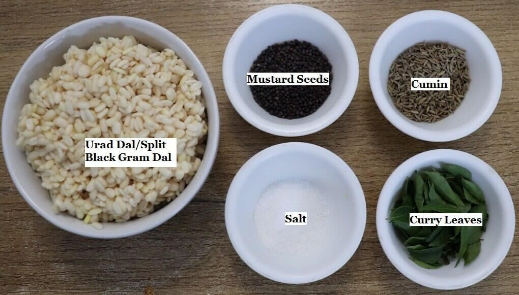 individually labeled ingredients to make kuvalyacho vadyo recipe are laid out on a table.