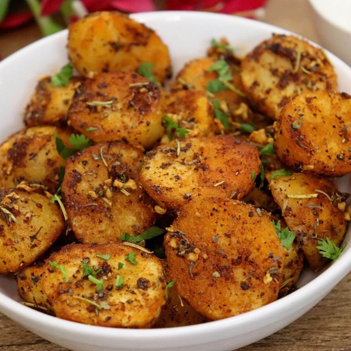 close-up of roasted mediterranean potatoes in a white colored bowl.