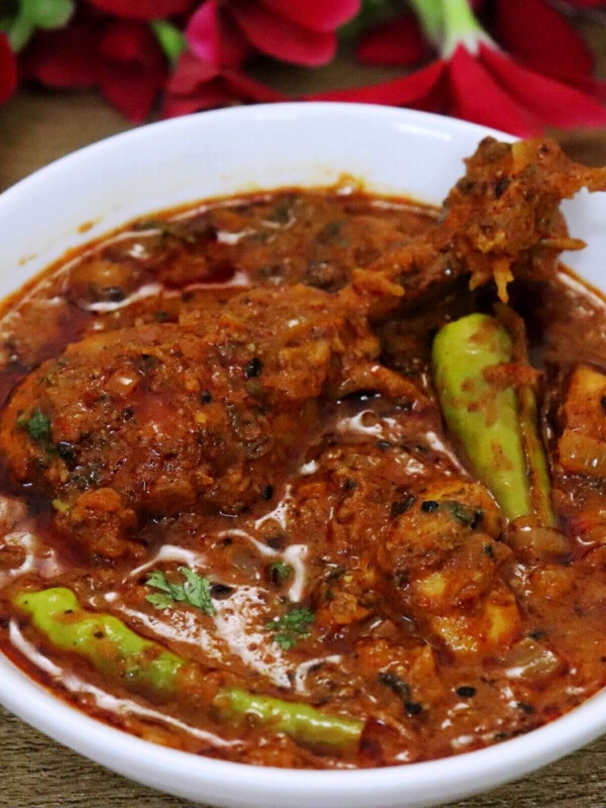 close-up of achari chicken served in a white bowl.