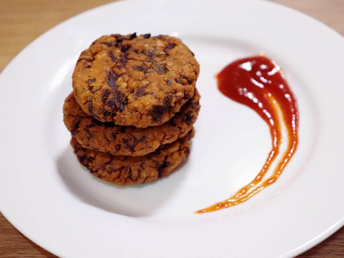 close-up of chattambade. It shows 3 chattambade stacked on a white plate. It is served with tomato sauce.