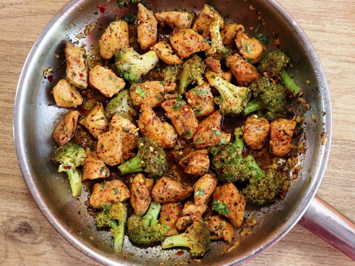 a tight close-up of chicken and broccoli stir fry in a skillet.