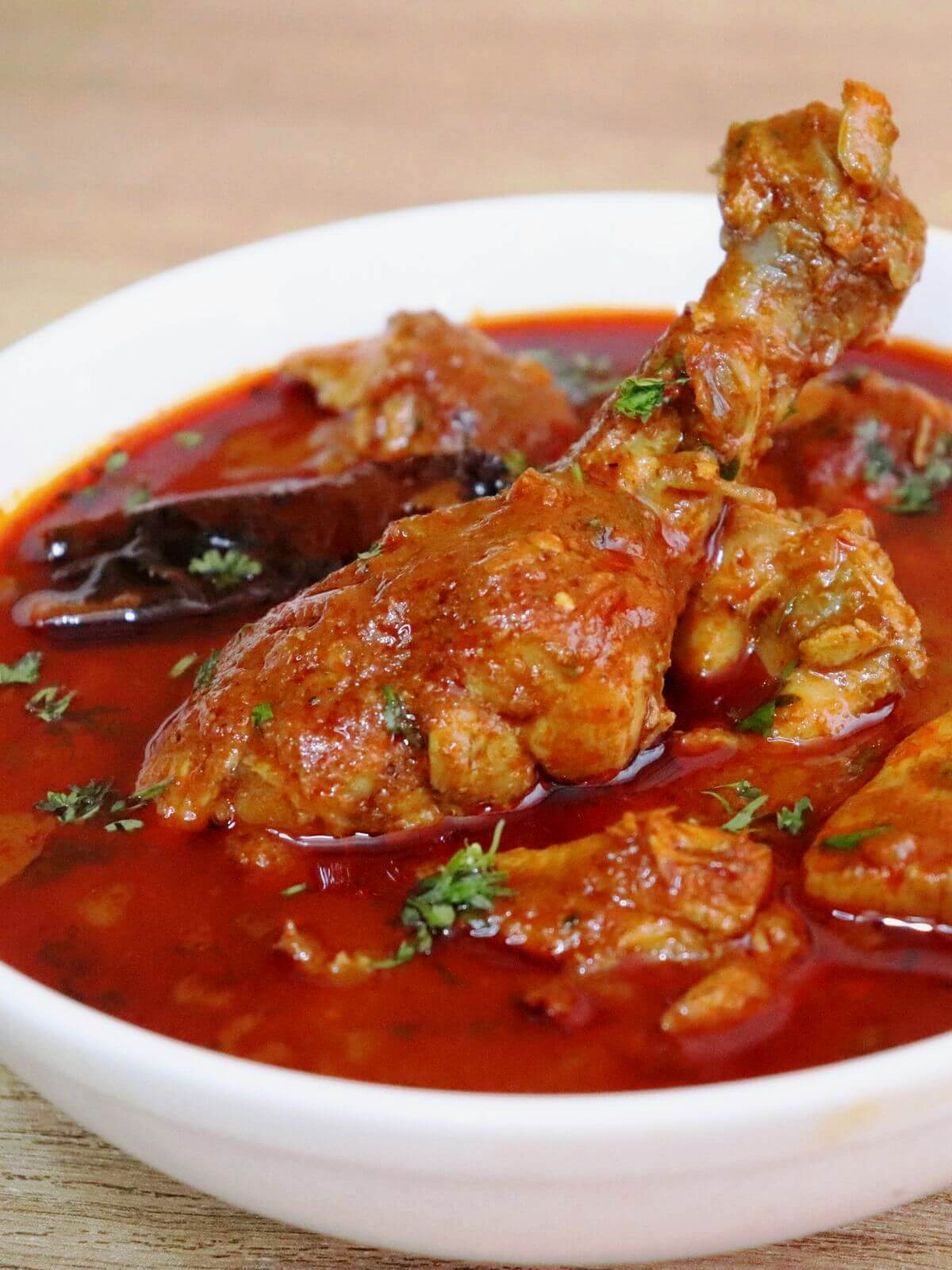 a tight close-up of chicken kolhapuri curry in a bowl.