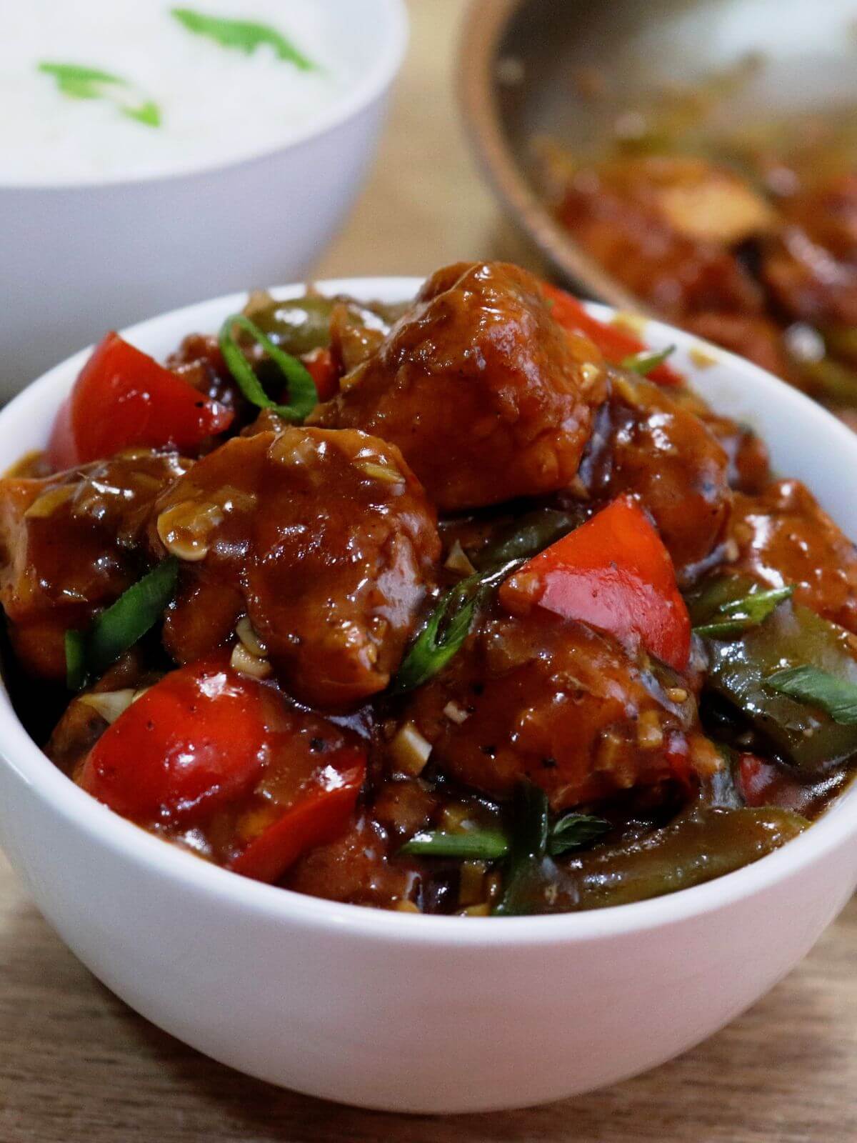 tight close-up of chilli chicken gravy served in a white bowl.
