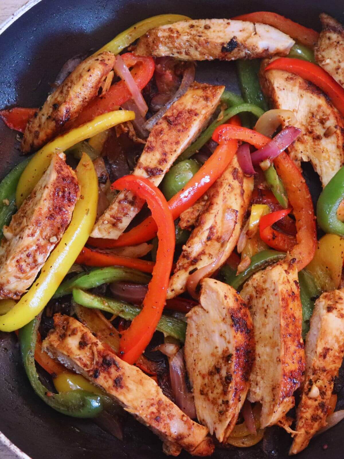 tight close up of chicken fajitas in a pan.