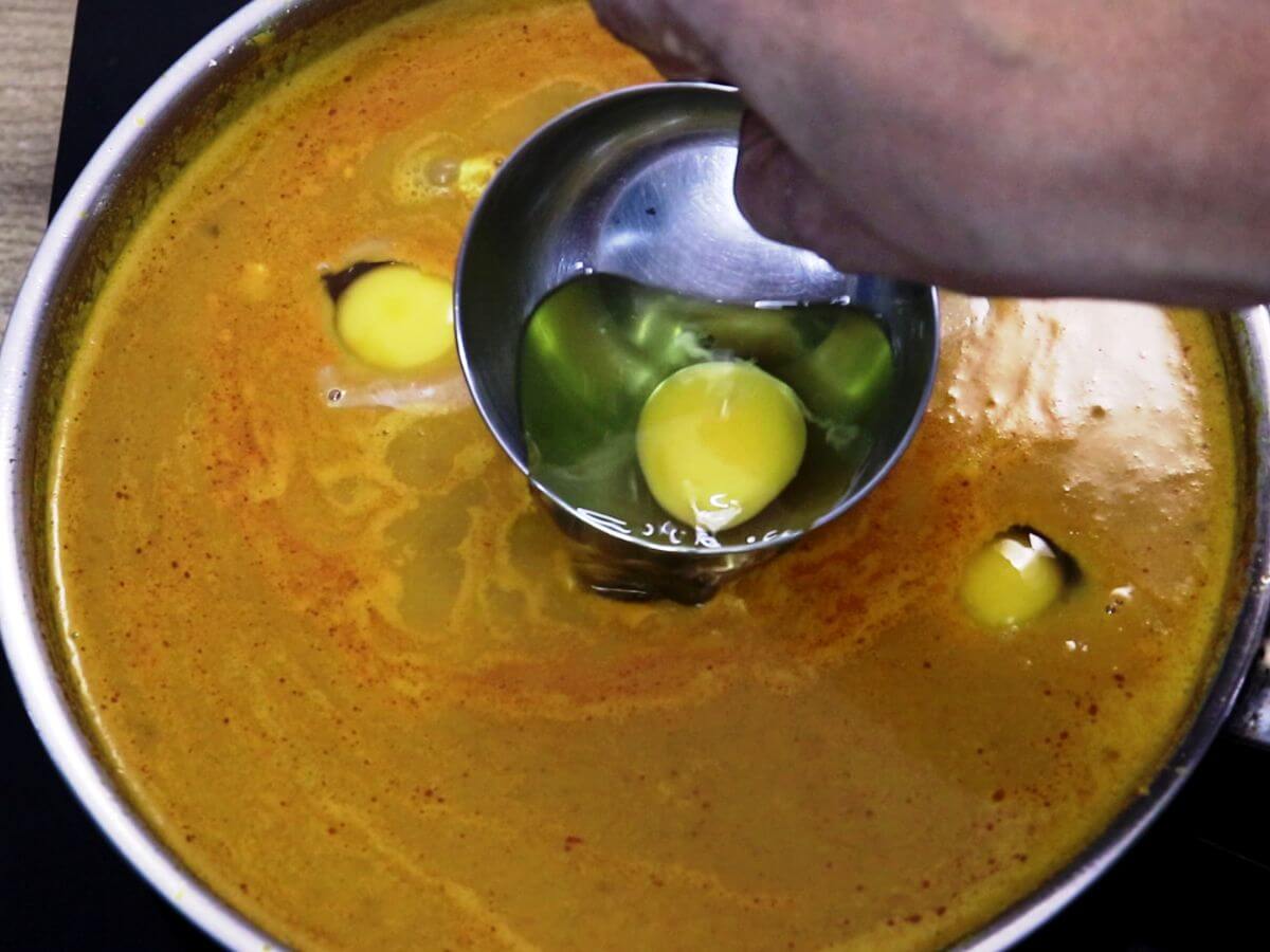 addition of eggs to the curry. It shows cracking each egg into a small bowl, then gently pour it into the curry.