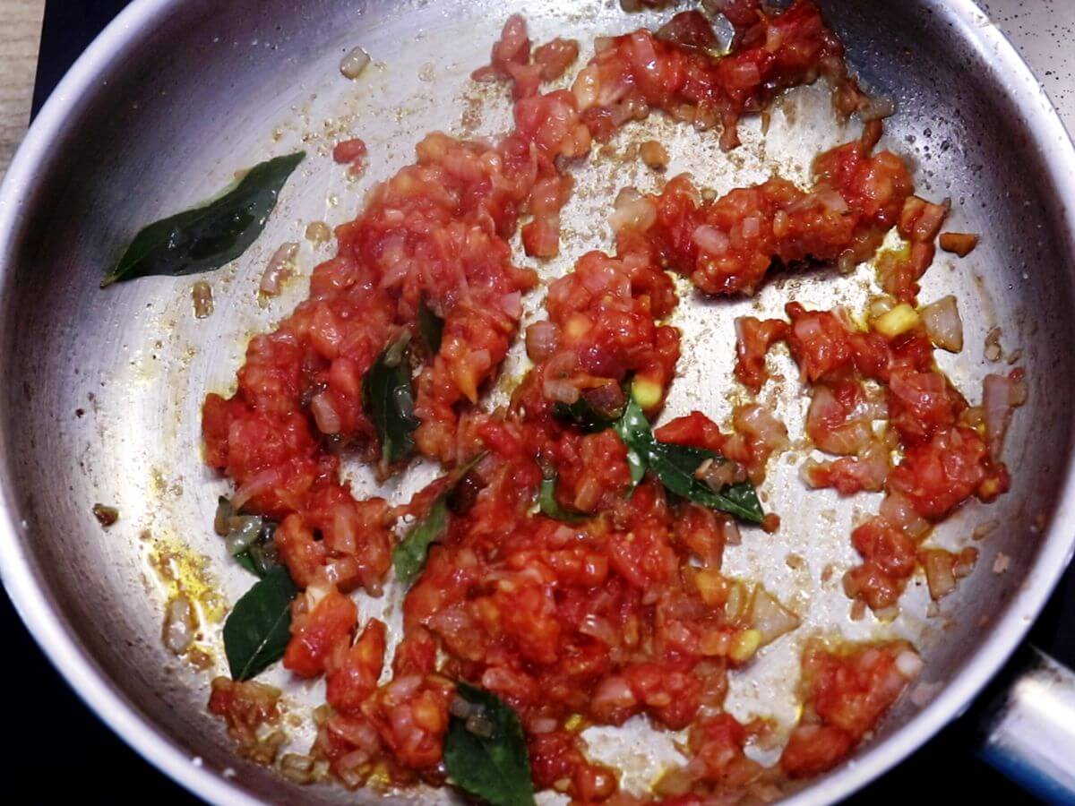 addition of tomatoes and curry leaves and cooking them for making mangalorean egg drop curry.