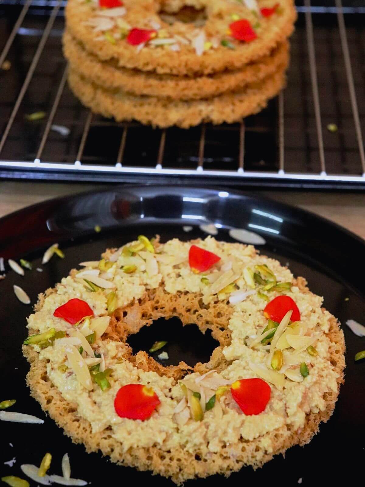 close-up of ghevar. It is served with rabri on top and garnished with almonds and pistachios.