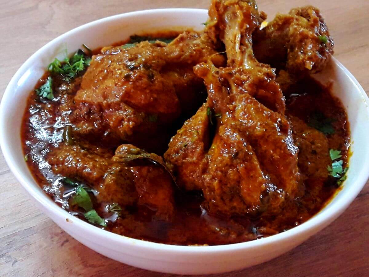 close-up of hyderabadi chicken masala curry served in a white bowl.
