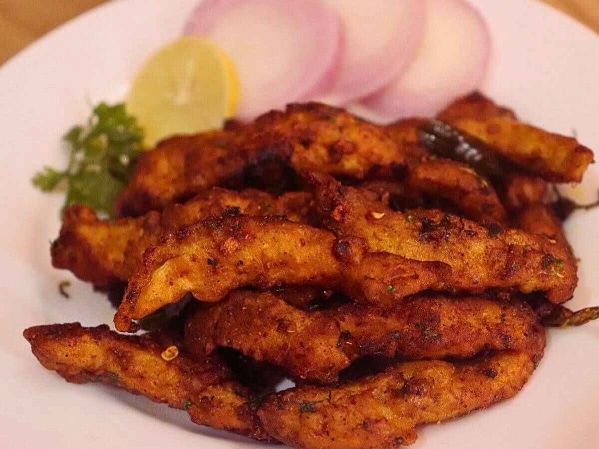close-up of hyderabadi chicken majestic served on a white plate with onion slices and a lemon slice.