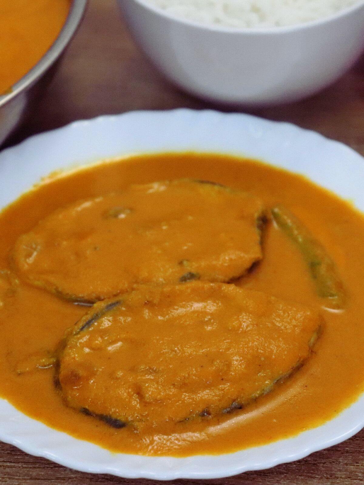 close-up of kingfish curry served in a white plate.