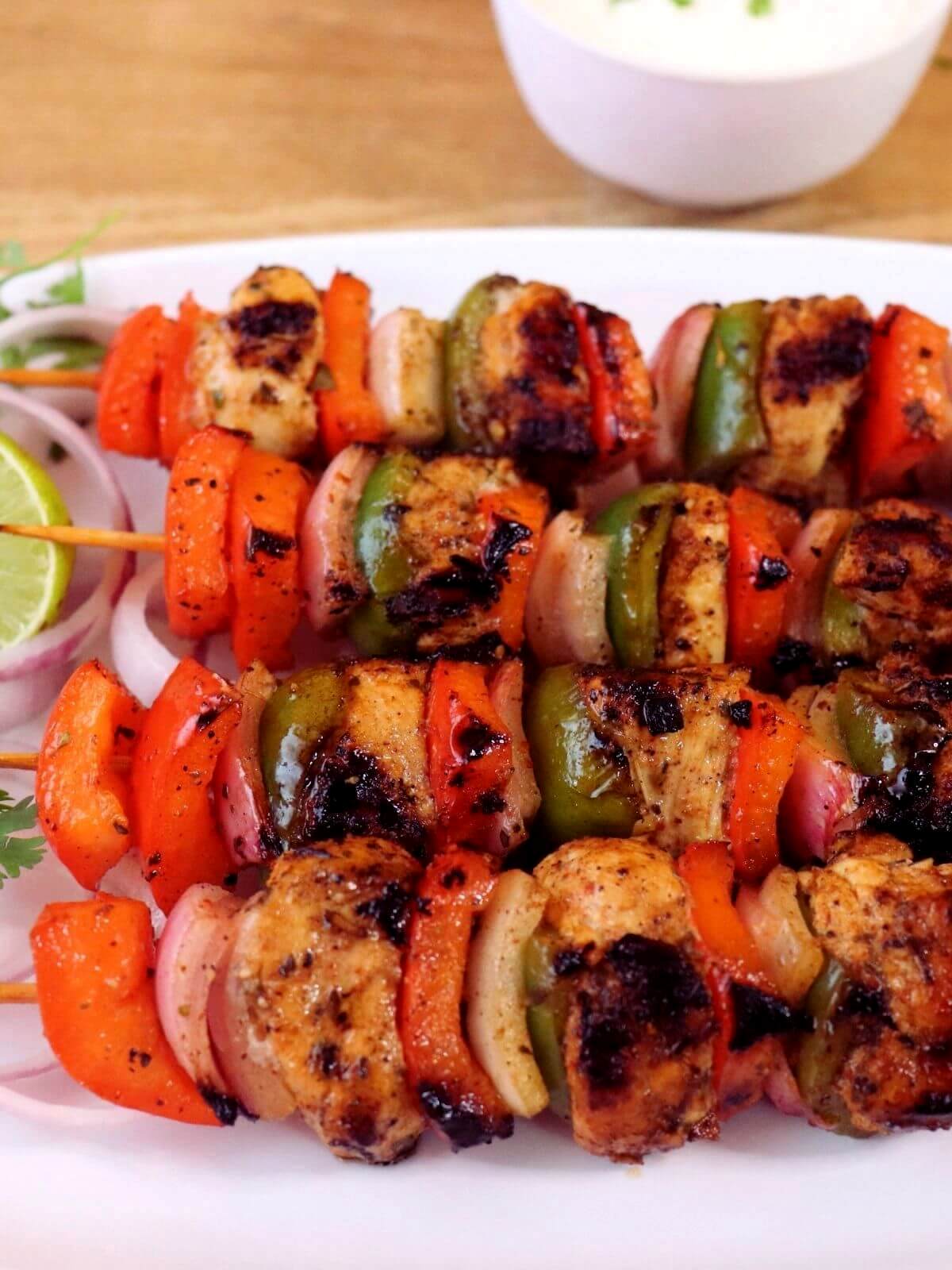close-up of mediterranean grilled chicken kabobs. It shoes 4 chicken kabobs placed on a plate.