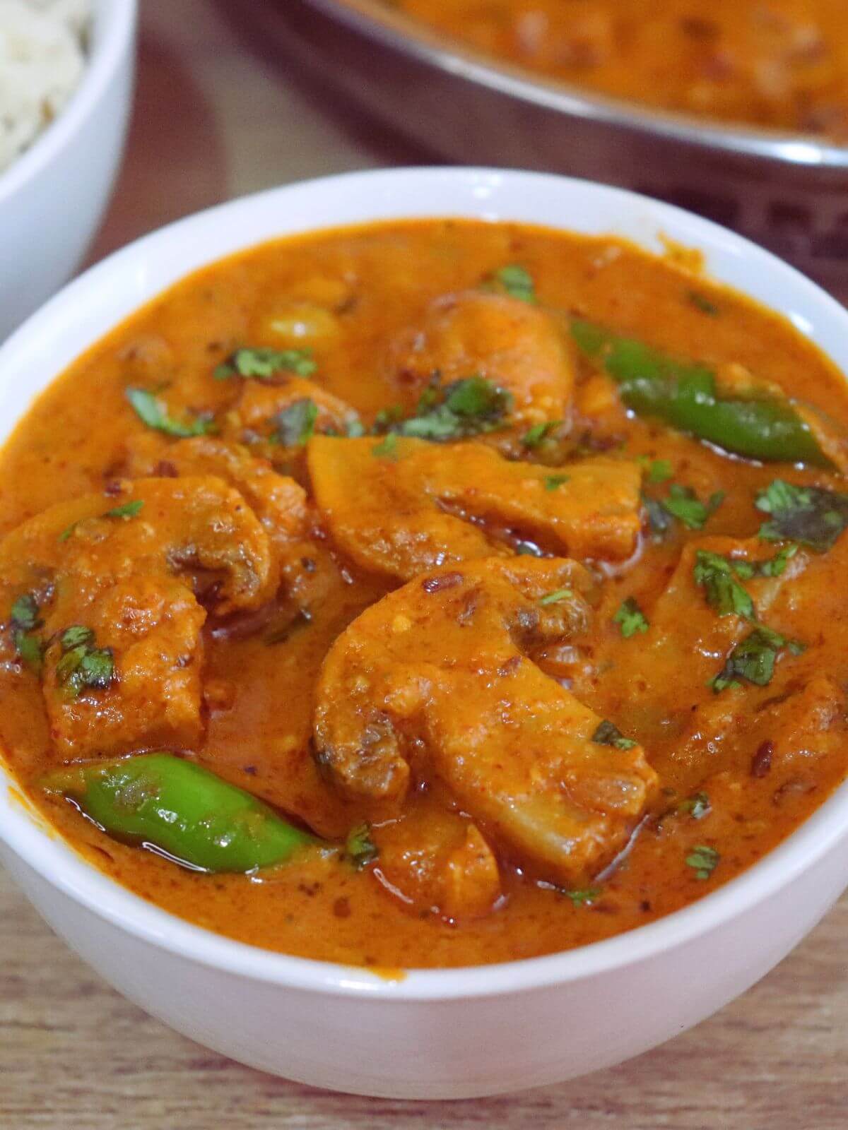 close-up of mushroom masala served in a white bowl.