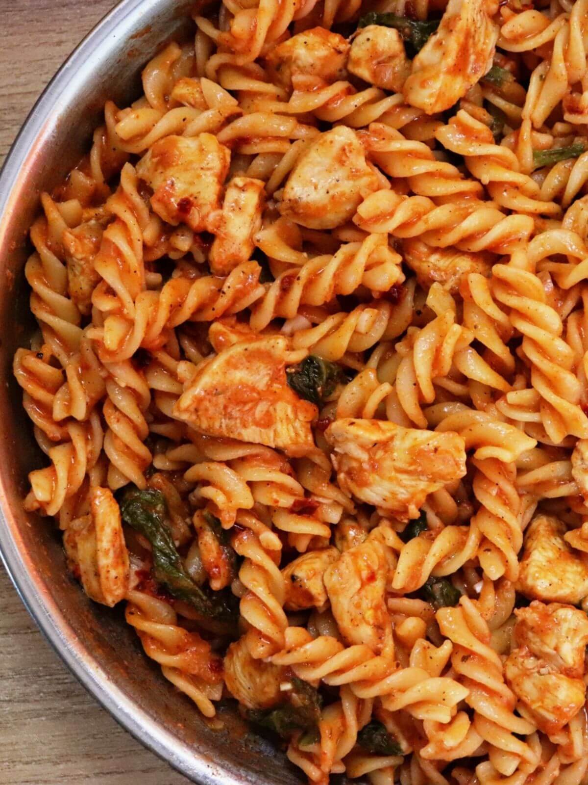 close-up of tomato spinach chicken pasta in a skillet.