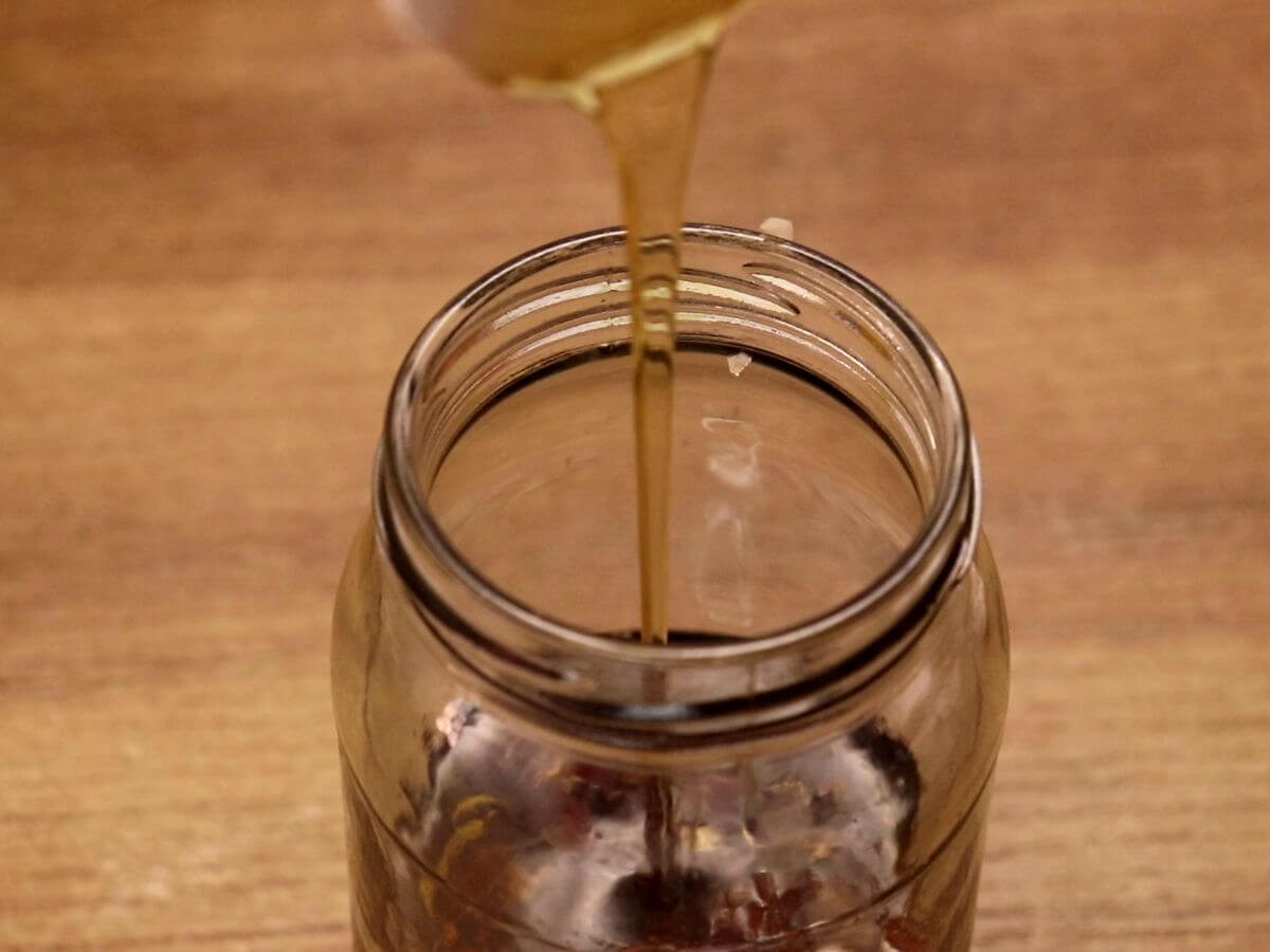 making asian slaw dressing. Pouring honey in the mason jar.