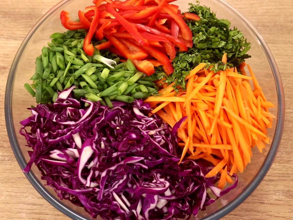 assembling all the vegetables in the mixing bowl to make asian slaw.