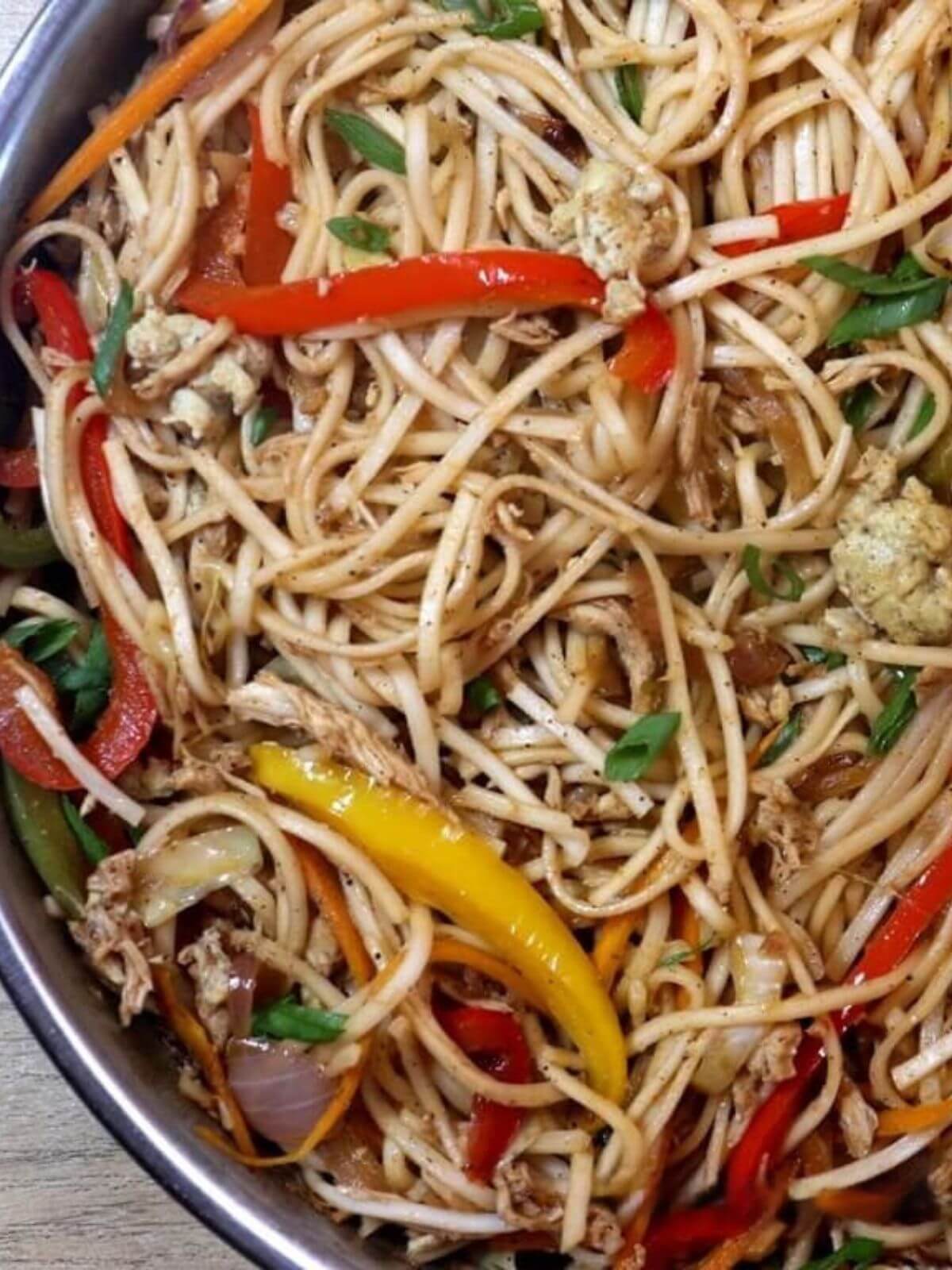 close-up of chicken hakka noodles in a skillet.