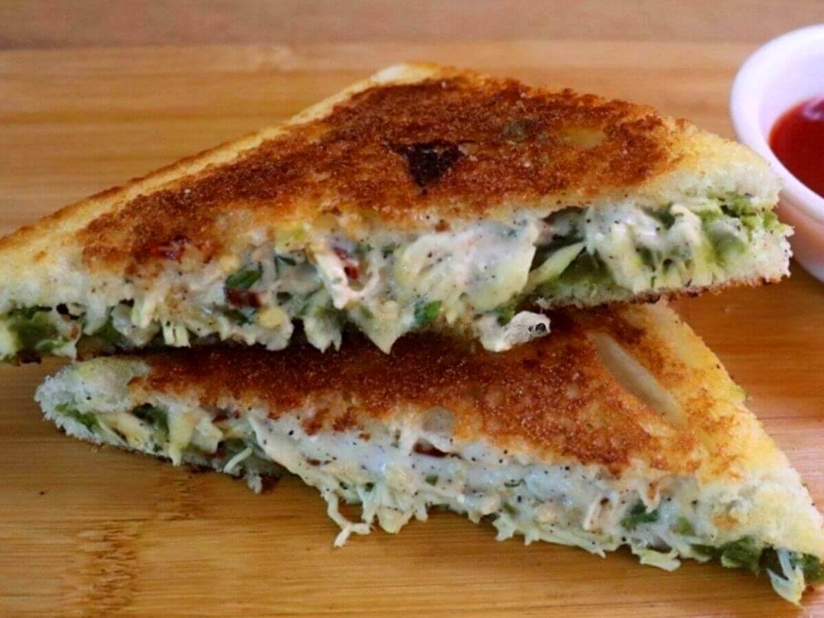 Close-up of a chicken mayonnaise sandwich, cut in half and stacked on a chopping board.
