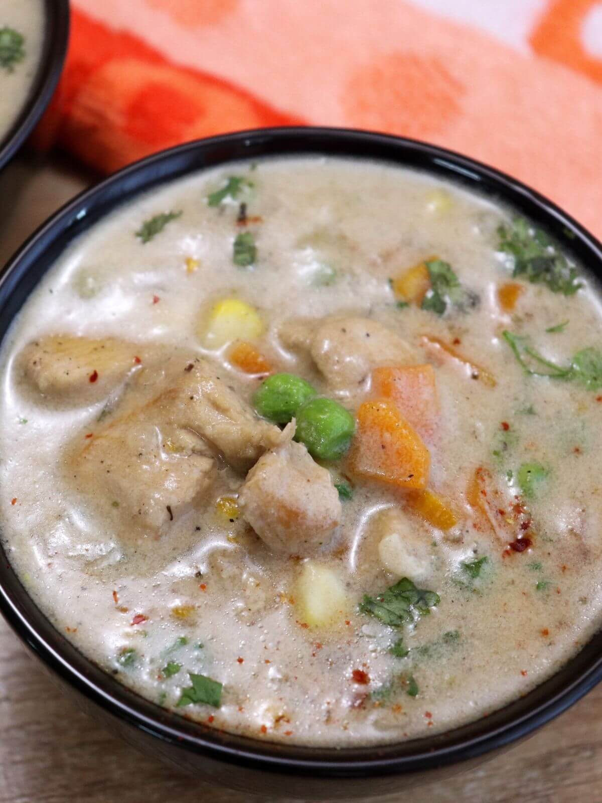 close-up of chicken stew served in a black bowl.