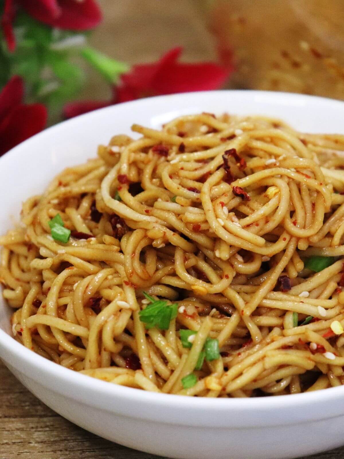 close-up of chili oil noodles served in a whte bowl.