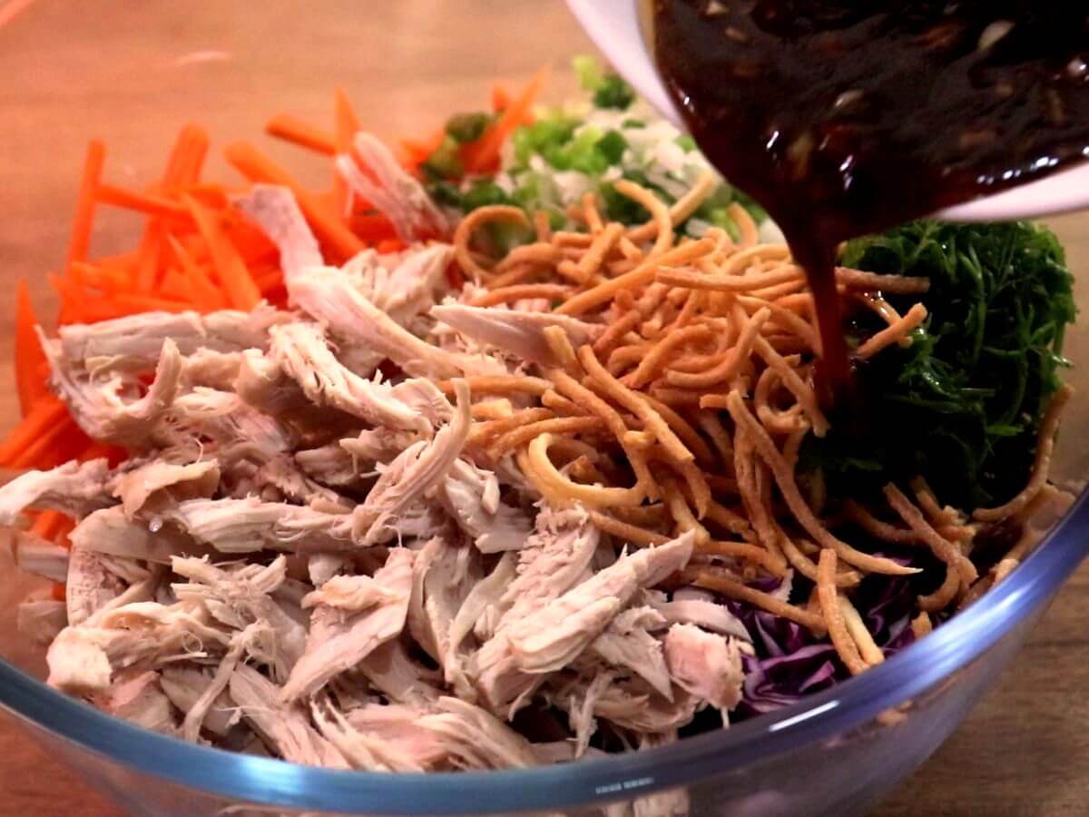 Pouring dressing on chicken salad.