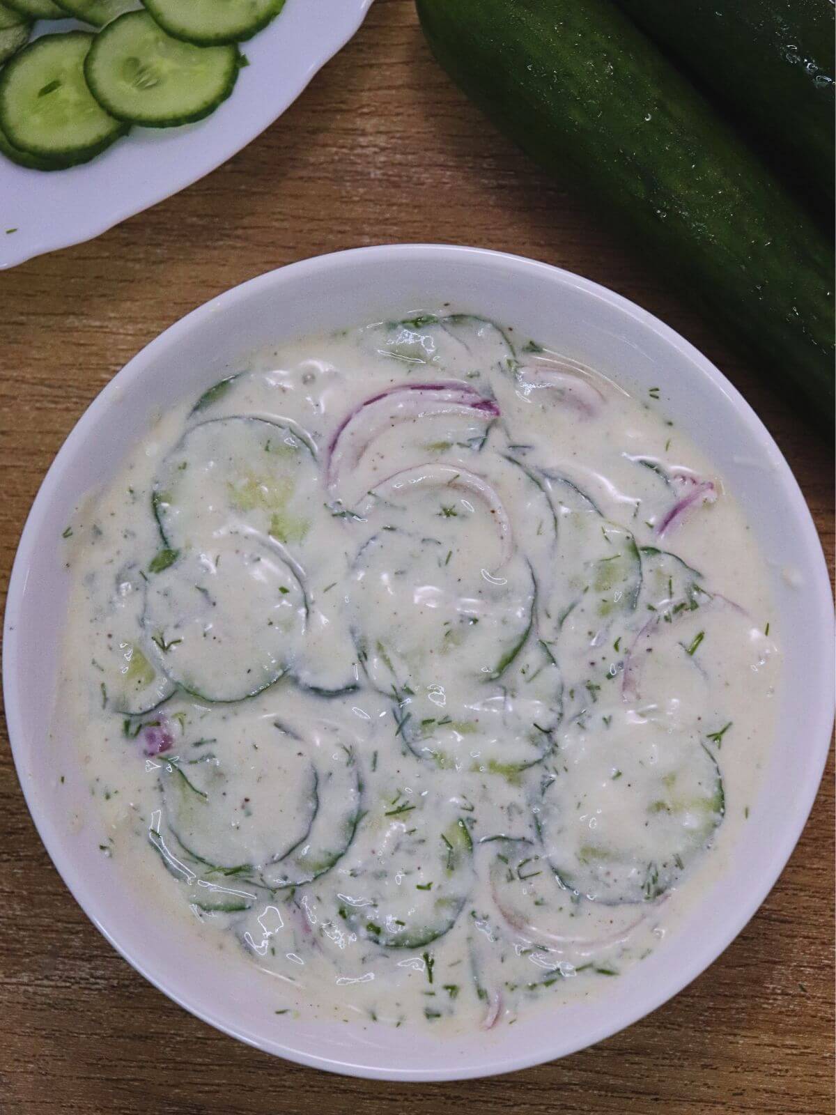 top view of creamy cucumber salad served in a bowl.