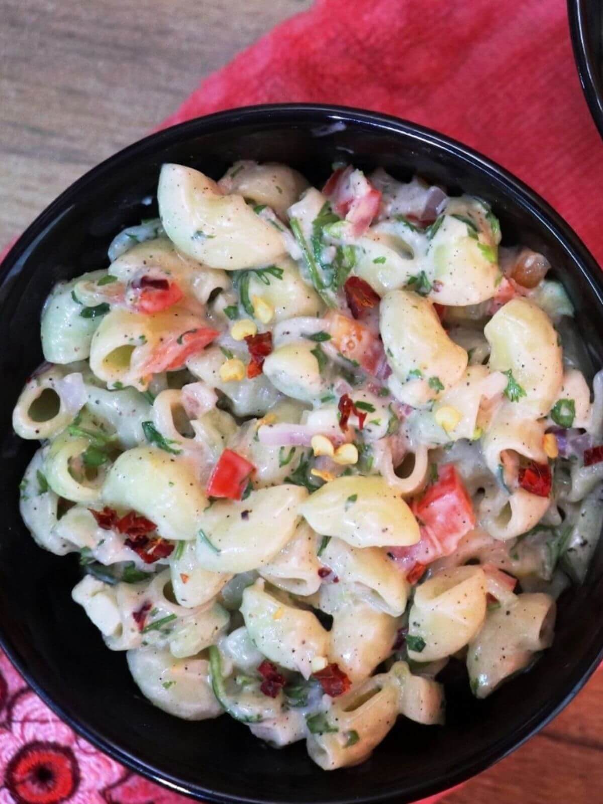 close-up of creamy macaroni salad in a black color bowl.