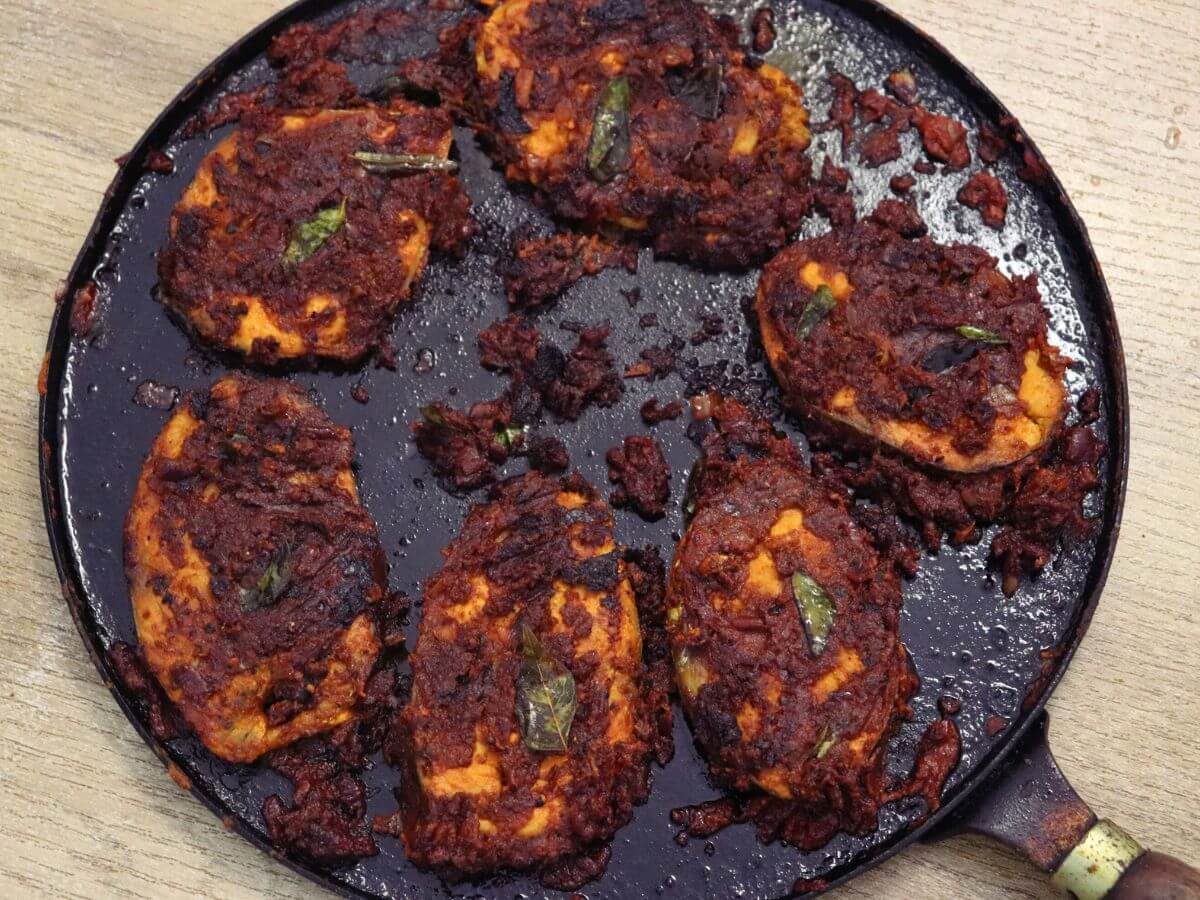 A close-up shows fish masala fry cooked on a tawa.