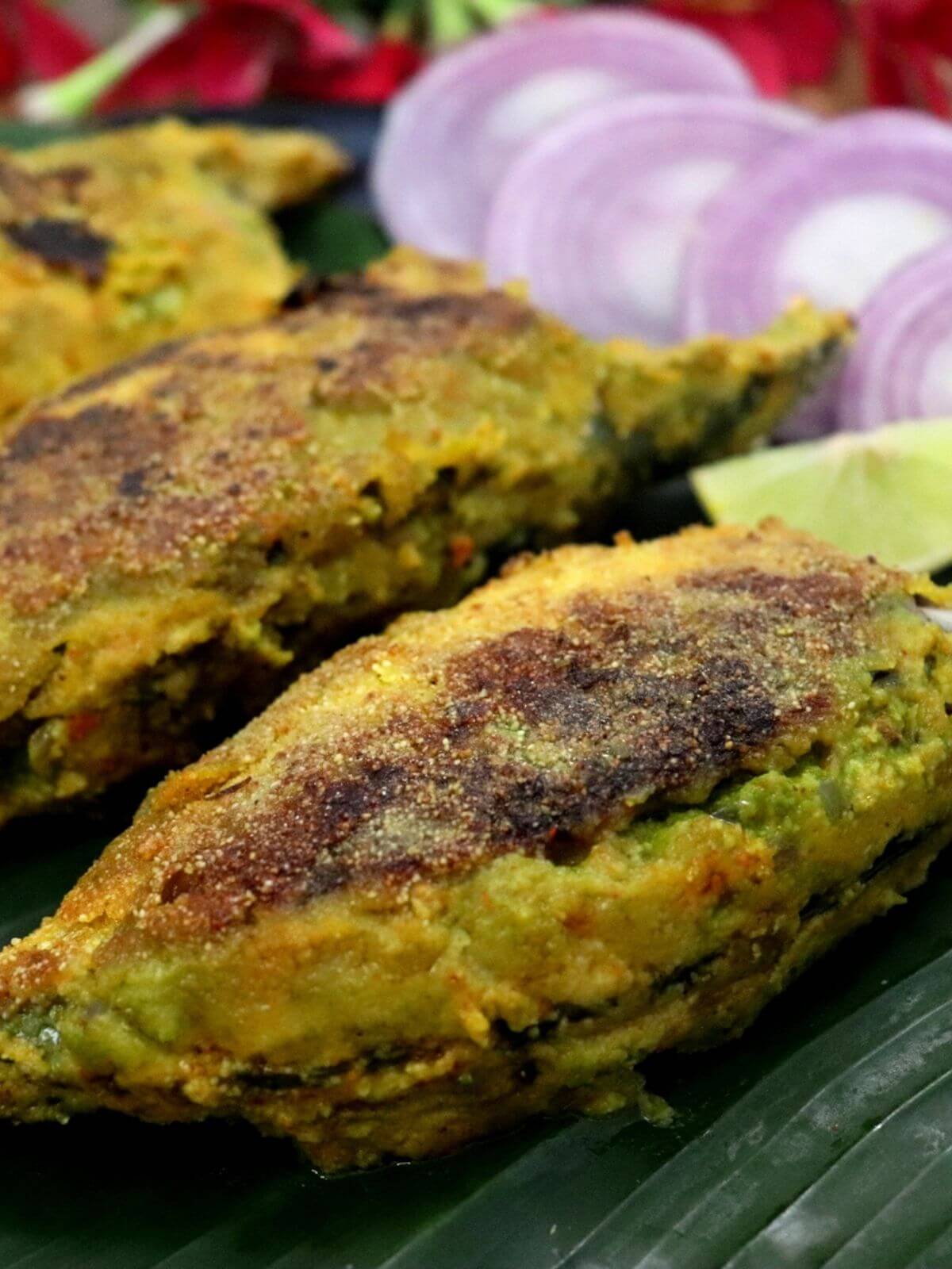 close-up of stuffed mackerel fish with green masala served on a banan leaf.
