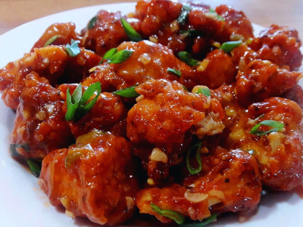 close-up of gobi manchurian served on a plate. Garnished with spring onion greens.