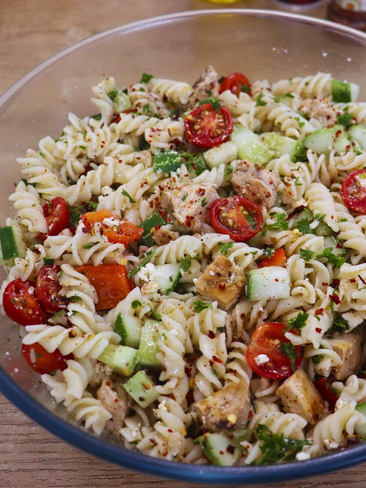 close-up of greek chicken pasta salad in a big mixing bowl.