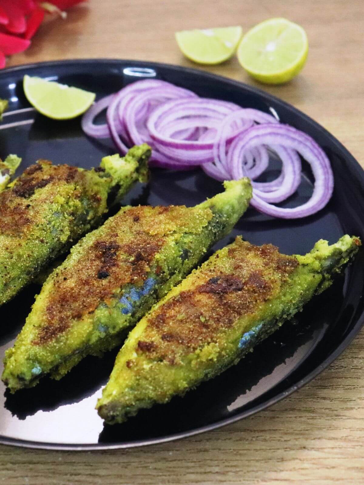 close-up of green masala fish fry served in a plate with onion rings and a lemon wedge.