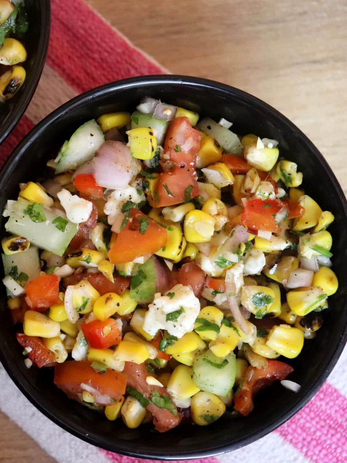 top-view of grilled corn salad with feta cheese in a bowl.