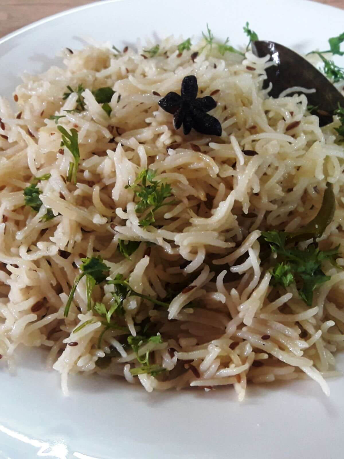 close-up of jeera rice served on a white plate.