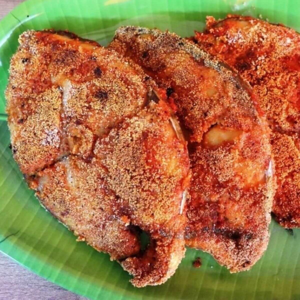 close-up of mangalorean rava fish fry served on a green plate.