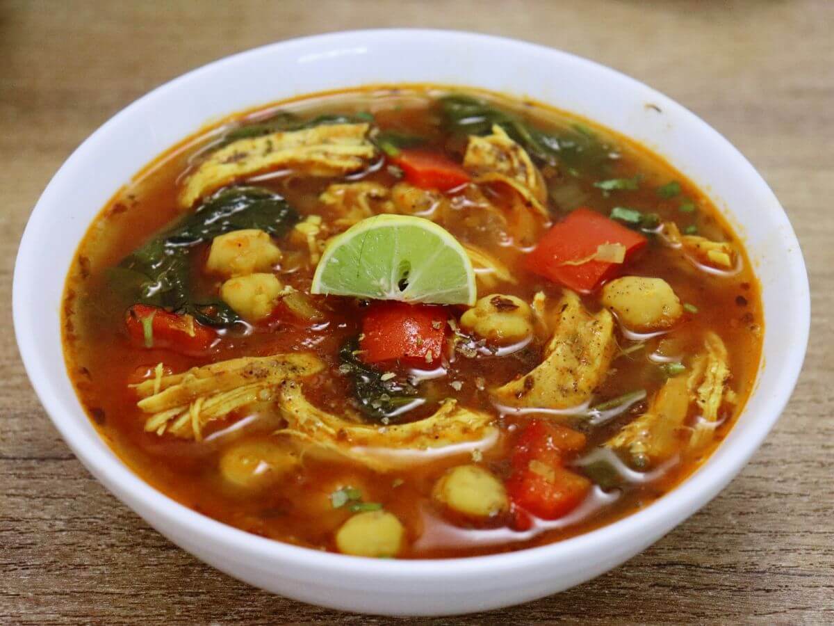 close-up of chicken and chickpea soup served in a bowl.