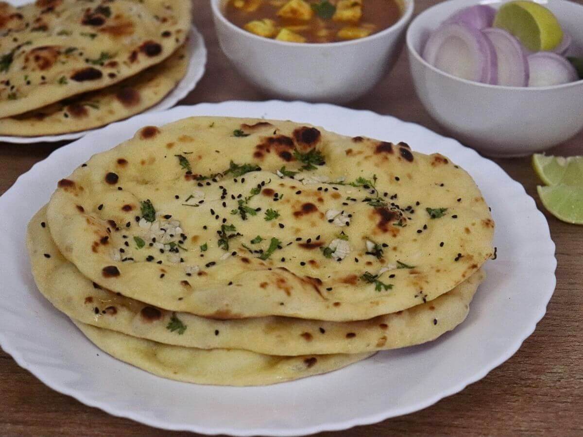 close-up of naan bread made with greek yogurt. It is served with a curry and salad on the side.