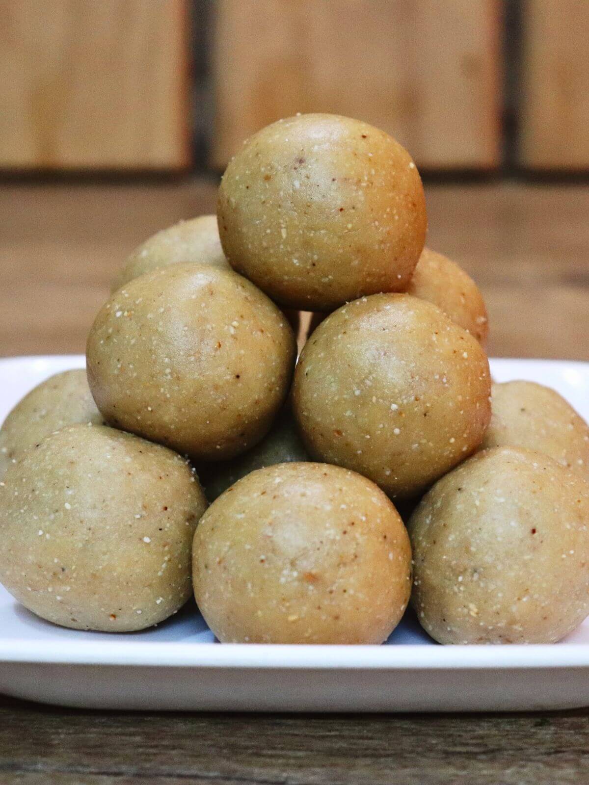 A close-up of peanut ladoo, stacked and served on a plate.
