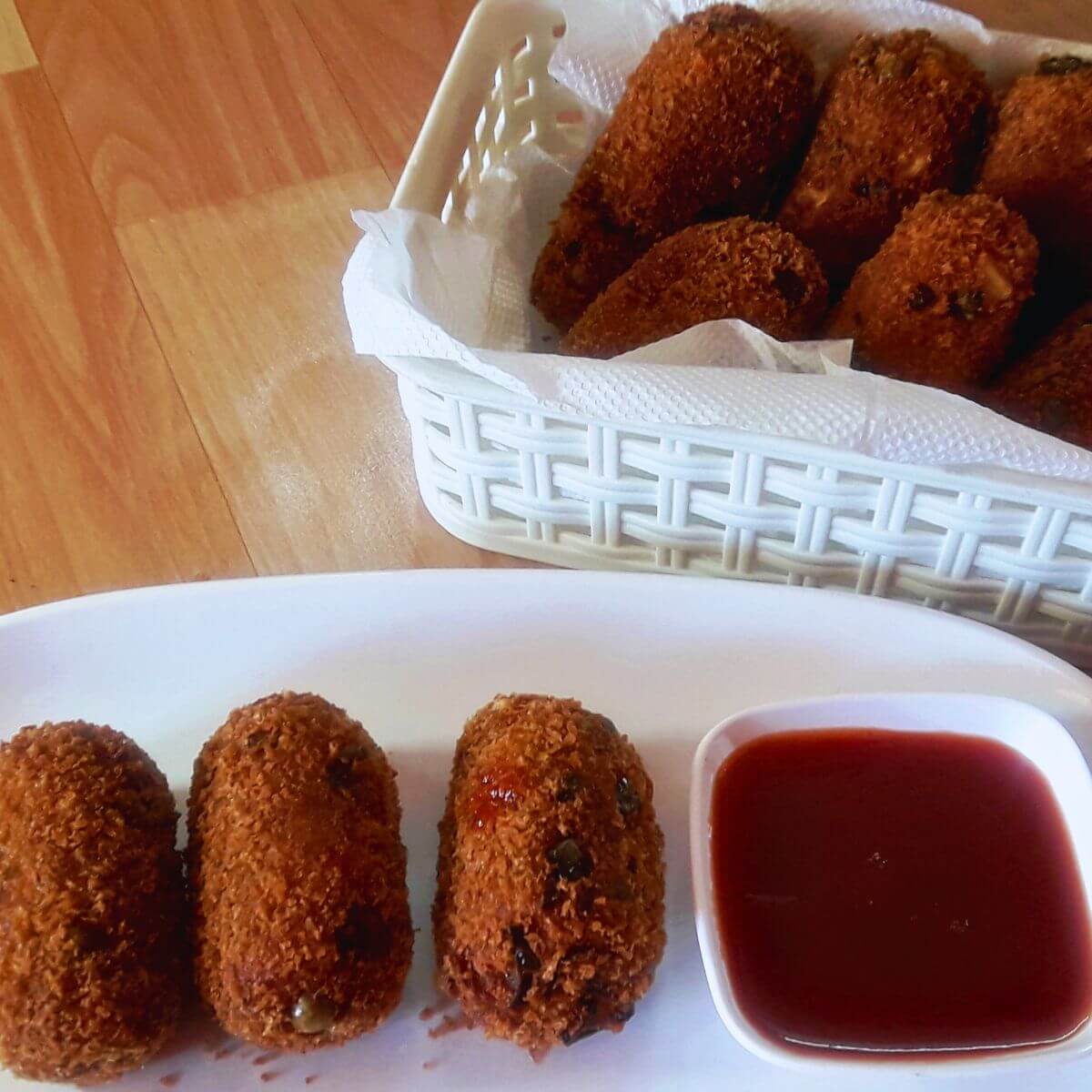 A close-up of vegetable nuggets, served with tomato ketchup in a small side bowl.