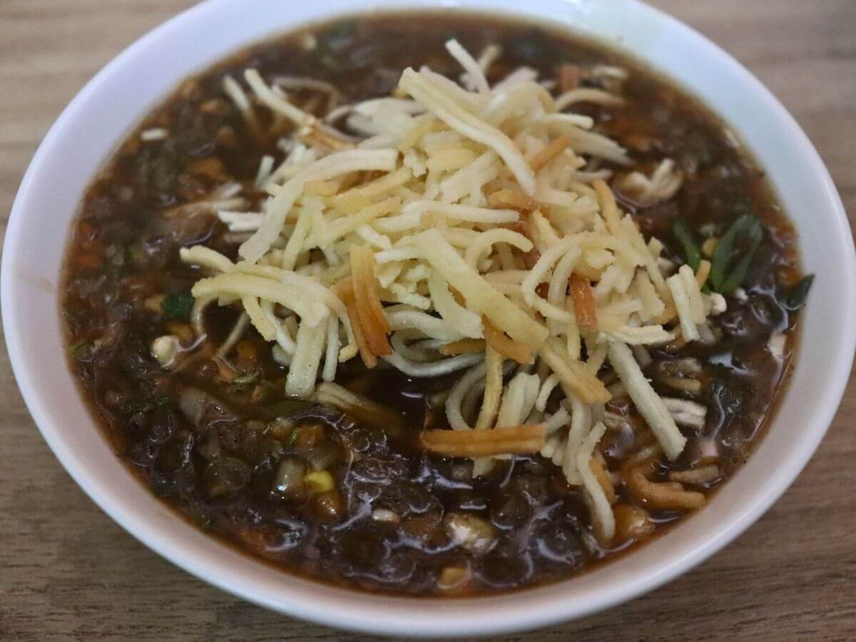 close-up of vegetarian manchow soup served in a bowl.